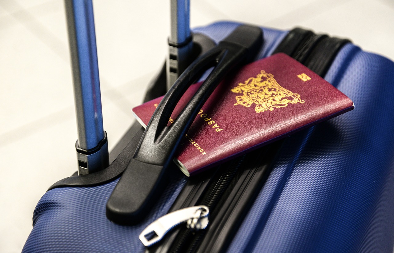 Czerwony paszport położony na niebieskiej plastikowej walizce podróżnej