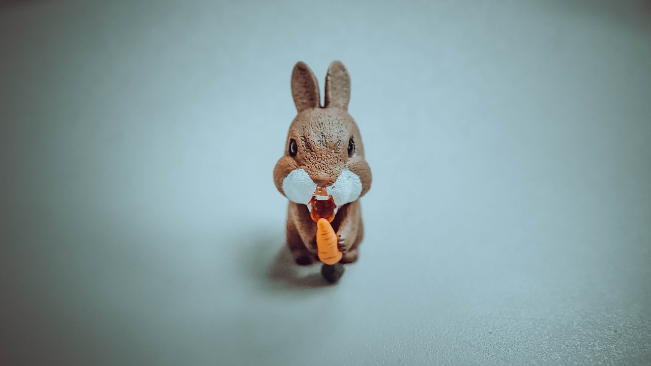 Figurka z brązu gnieźnieńskiego króliczka z marchewką na niebiesko-szarym tle