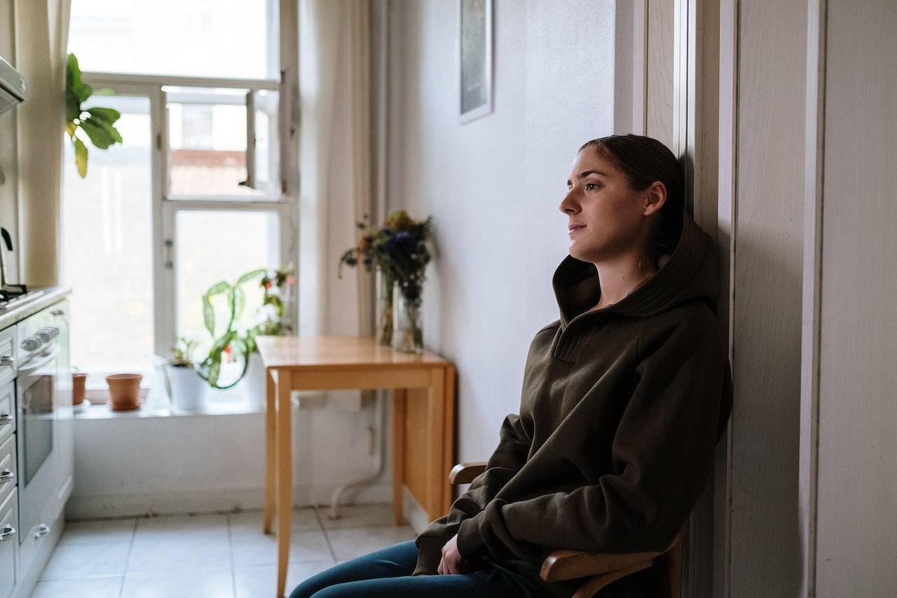 Kobieta z depresją siedzi na krześle przy ścianie